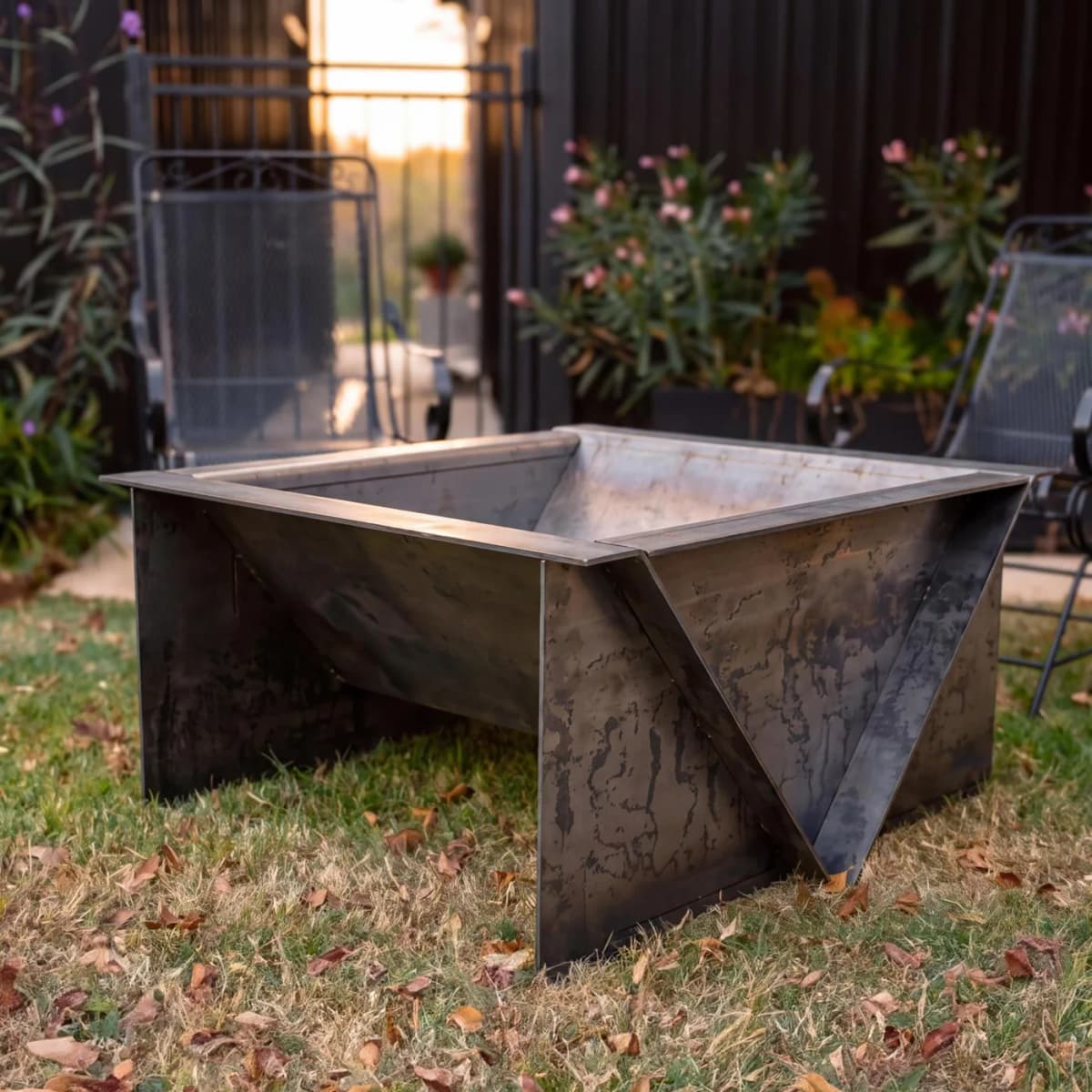 The Firepit 40 on a lawn in late-afternoon light, bare steel just starting to weather.